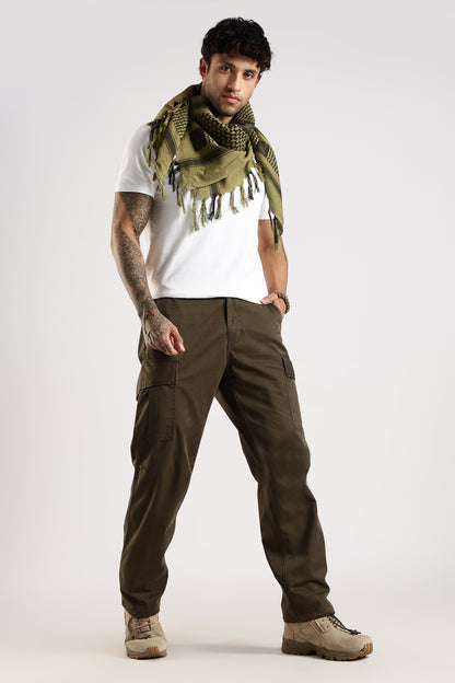 Man wearing an olive green tactical shemagh scarf in classic pattern, a white t-shirt and olive green cargo pants, on a white background